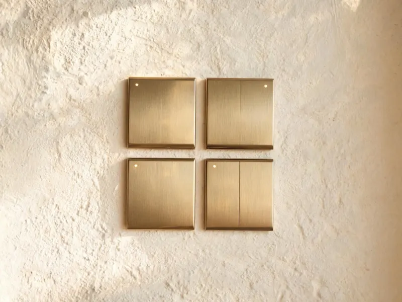 Tastsensoren aus gebürstetem Messing an einer Wand aus Kalkputz (KI-generiertes Bild)